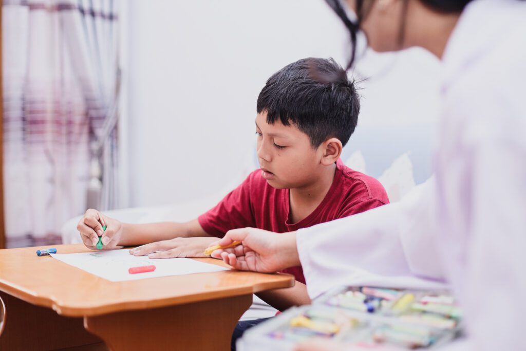 A boy sitting at a table with an adult.